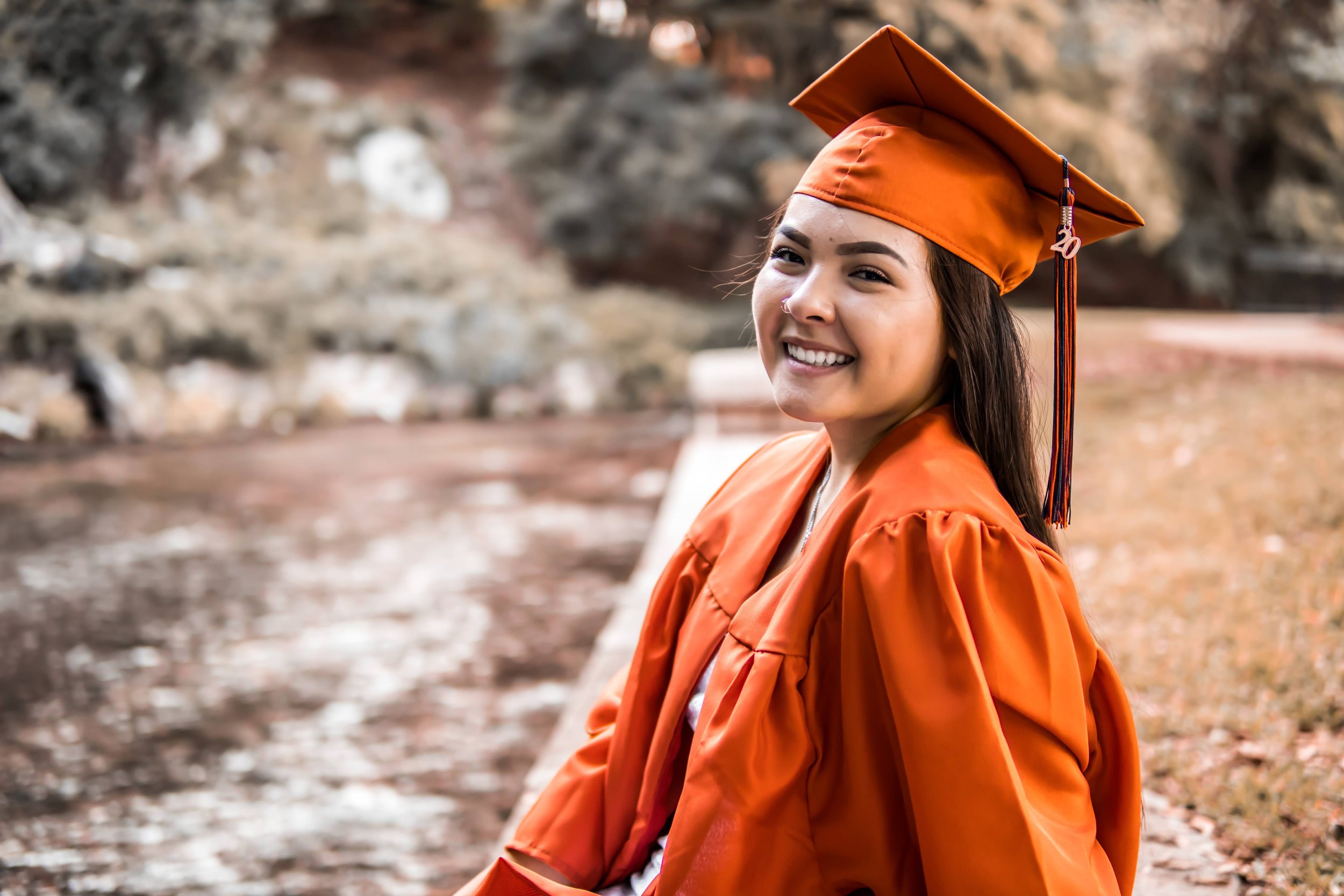 Graduate in an orange gown by a creek