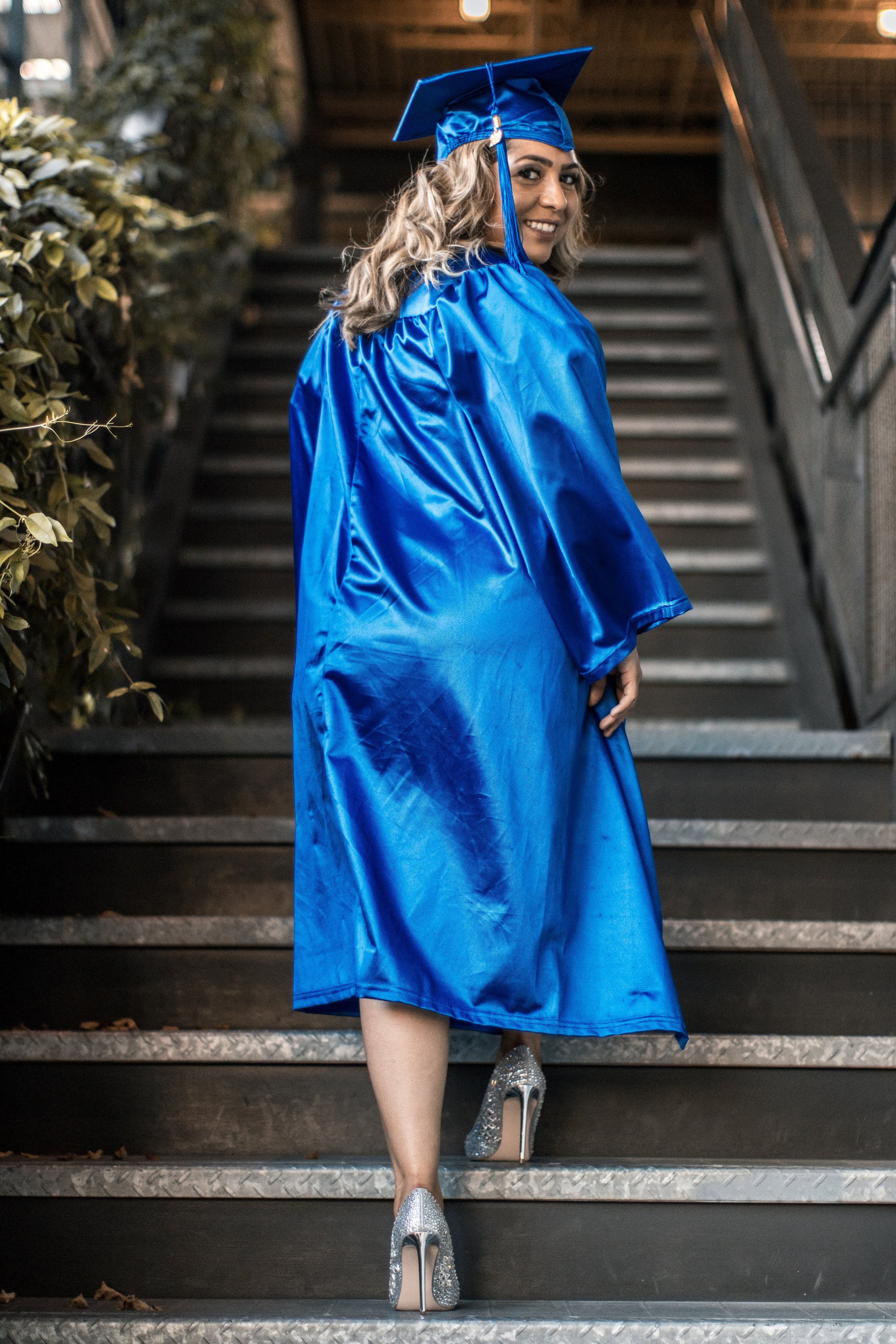 Graduate in a blue gown walking up stairs
